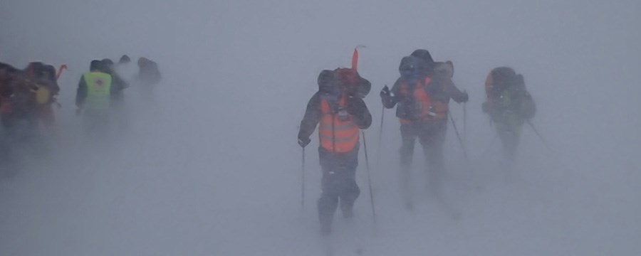 personer i hjelpekorps uniform som strever gjennomg en snøstorm