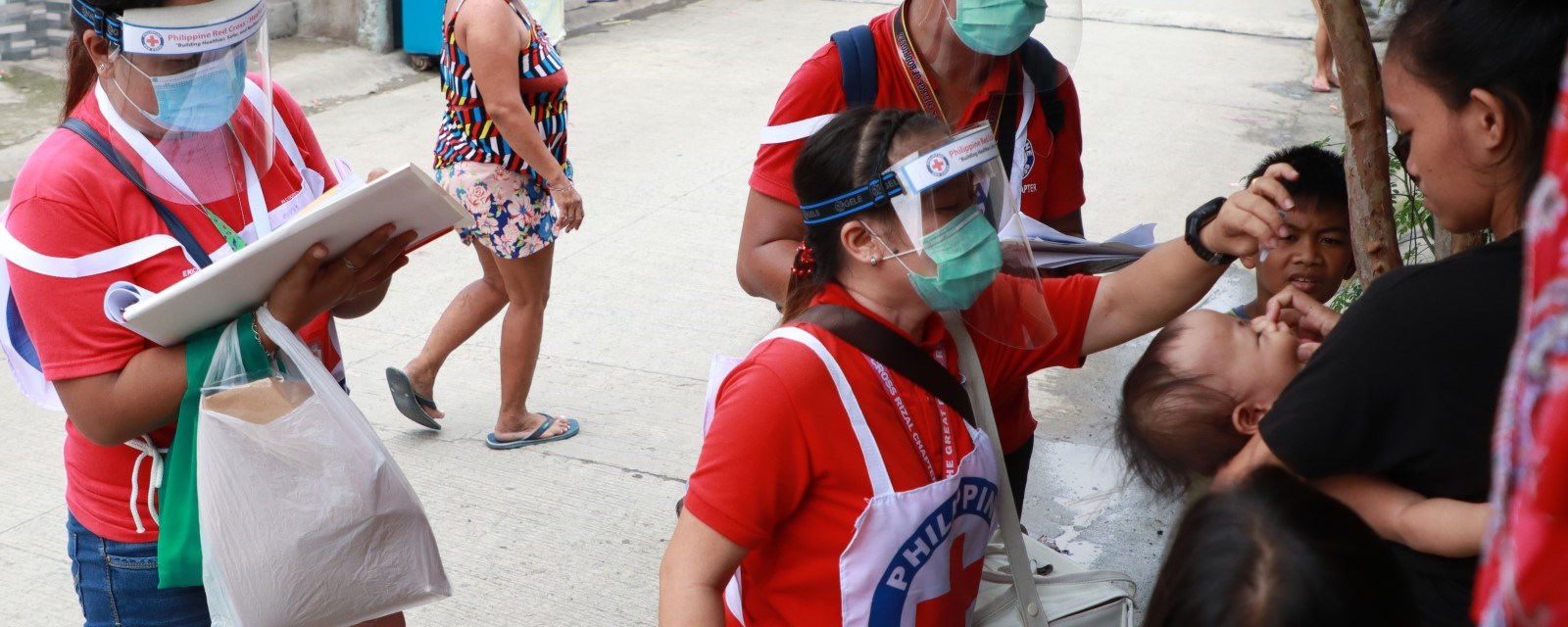 Tre frivillige fra Filippinene gir et lite barn vaksine