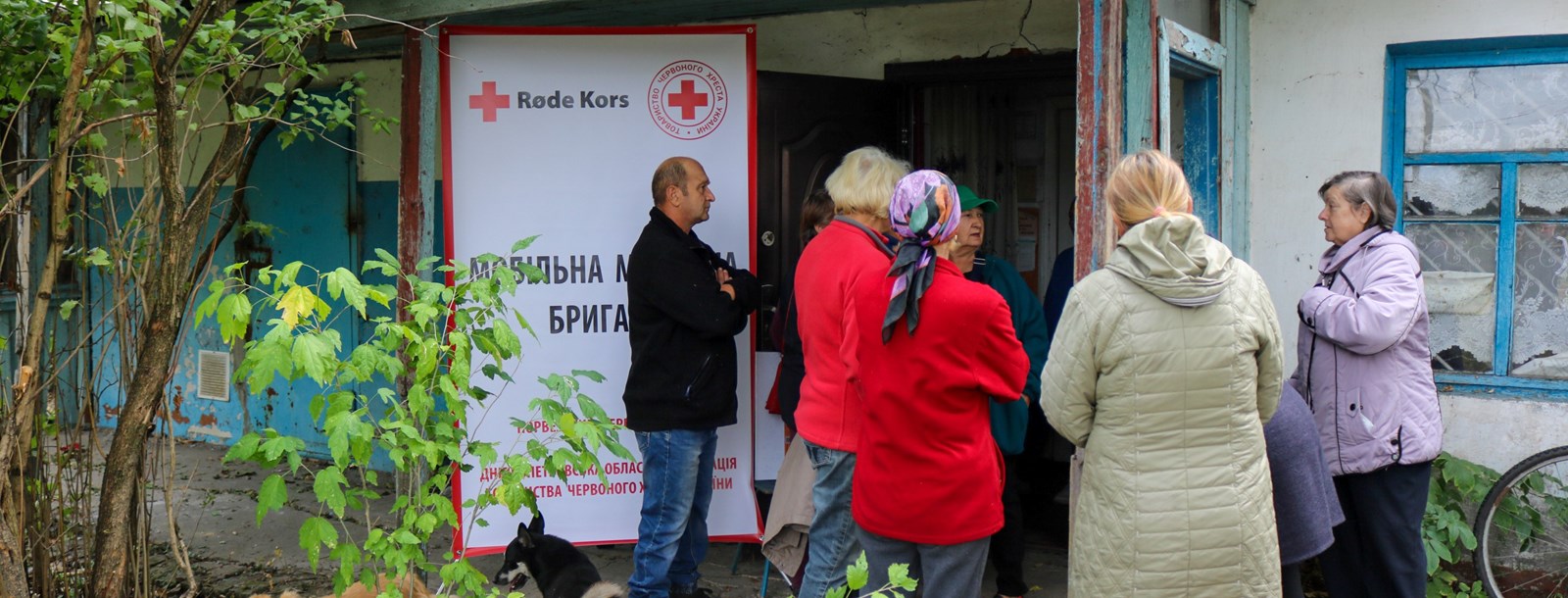 Bilde av eldre mennesker utenfor et hus der Røde Kors tilbyr helsehjelp i Ukraina.