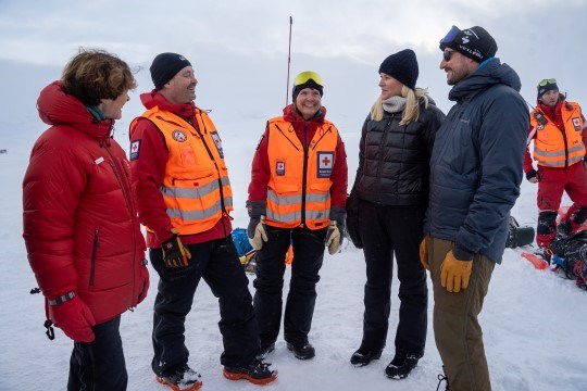 Gruppe mennesker står utendørs og snakker sammen.